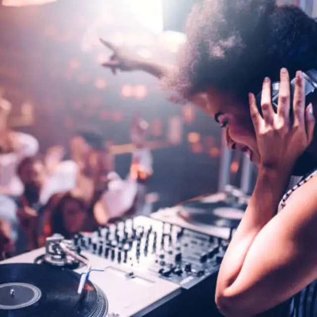Female DJ in headphones at the decks in a packed club